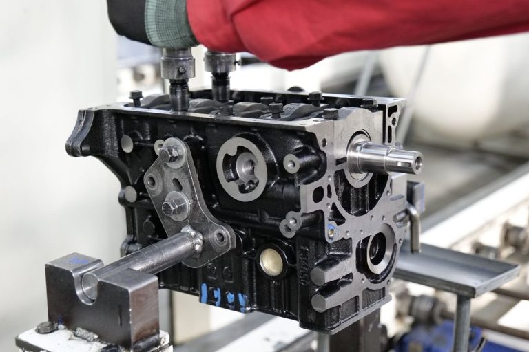 Close de um processo industrial de montagem de motores automotivos, com destaque para a precisão dos componentes.