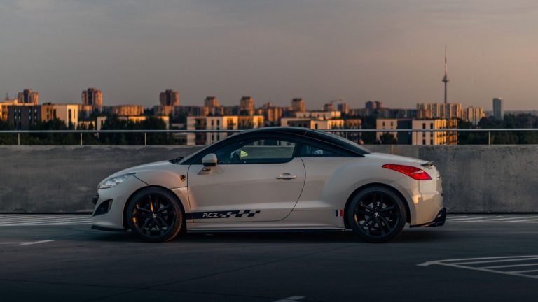 Peugeot RCZ branco visto de lado, estacionado ao ar livre durante o pôr do sol.