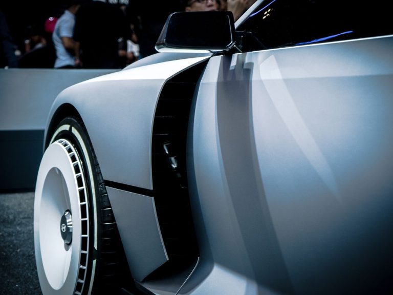 Carro-conceito futurista exposto em um salão automotivo, com desenho aerodinâmico e linhas modernas.