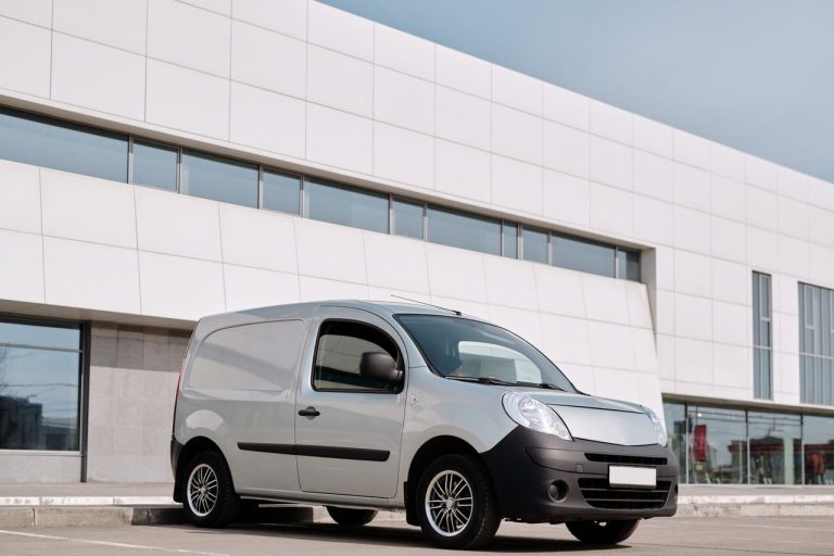 Renault Trafic 2027 ganha tecnologia, segurança e novas opções elétricas na Europa Van branca de entrega estacionada em frente a um edifício moderno.